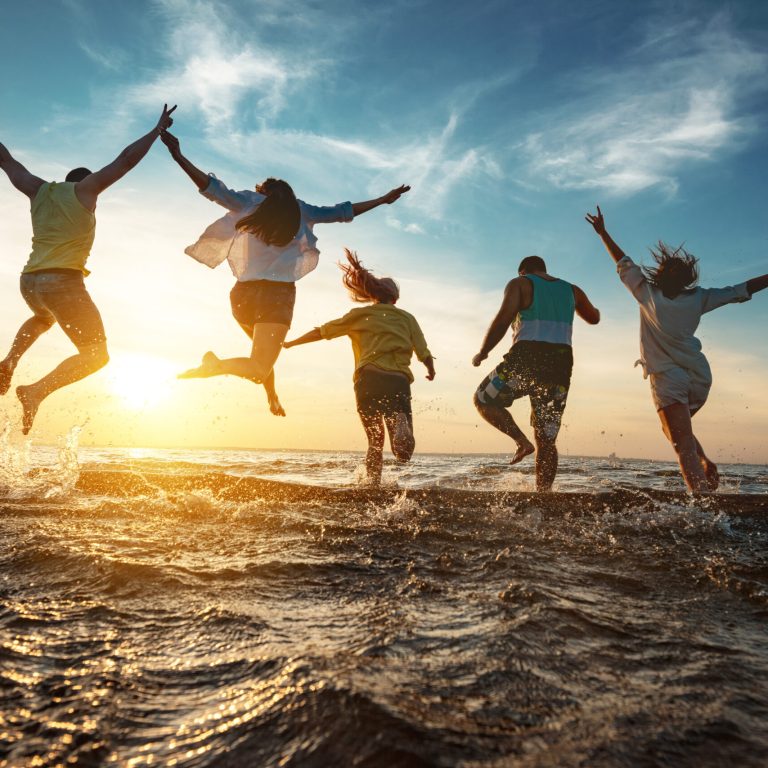 Five happy friends runs and jumps to sunset lake beach after party